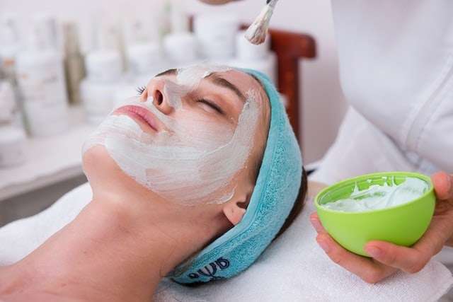 A woman lays with a face mask at a beauty salon.