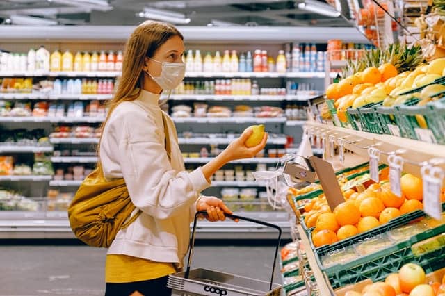 A woman buying lemon at a grocery store.