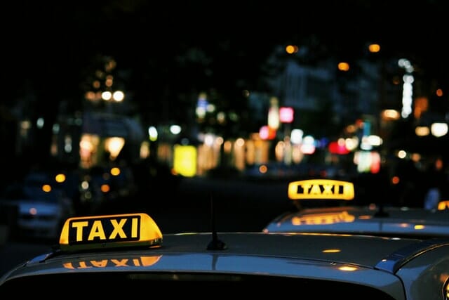 Two taxi vehicles with their lights on.