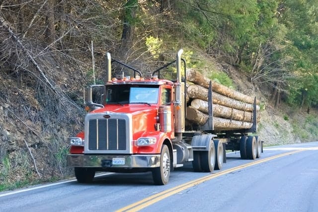 A red log truck hauling wood.