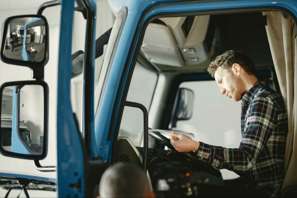 Man sitting in a blue truck reading bobtail insurance cost and policy.