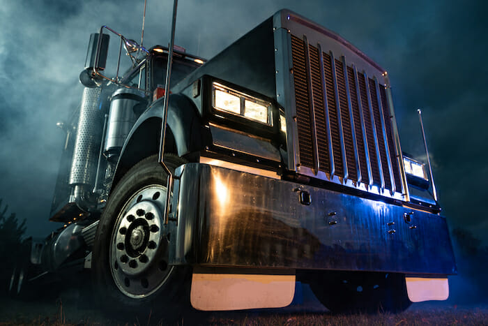 Retro Semi Truck Tractor Night Time Bluish Illumination and Foggy Atmosphere. Trucking Concept. Transportation Industry Theme.